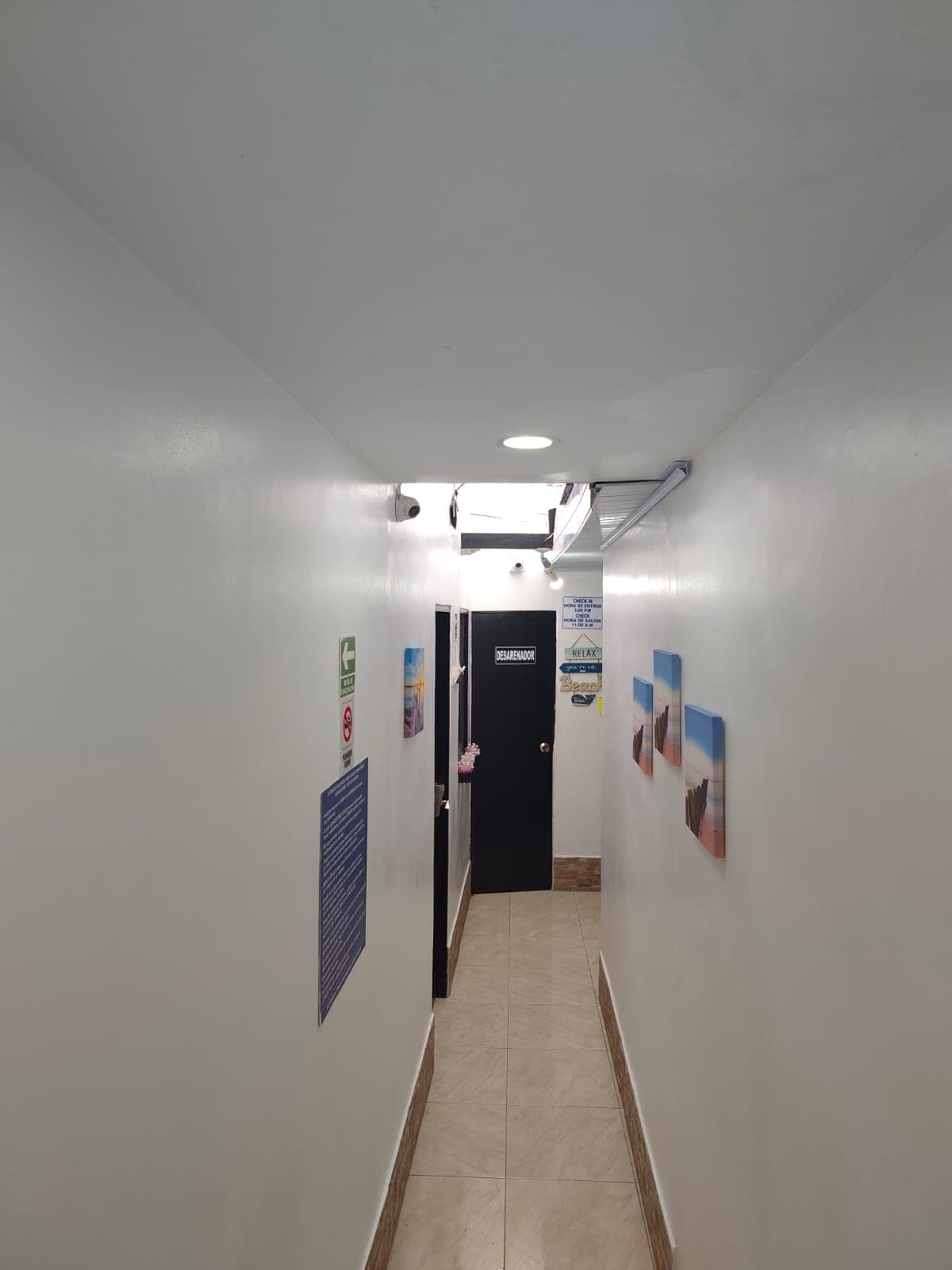 A hallway with a door labeled 'DESARENADOR' and a sign indicating a check-in time of 5:00 AM.