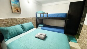 A room with a bunk bed, a single bed with matching pillows, a wall-mounted painting, and a wardrobe. - Hostal San Andres Vive (San Andrés)