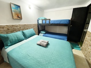 Una habitació amb un llit superposat, un llit individual amb almoinades a joc, un quadre penjat a la paret i un armari.