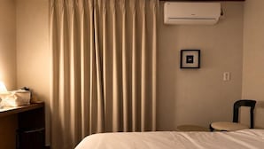 A hotel room with a bed, a desk with a chair, an air conditioning unit, and a picture on the wall. - Stay PAUSE (BUCHEON)