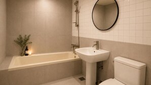 Et badeværelse med badekar, vask, toilet og et spejl.