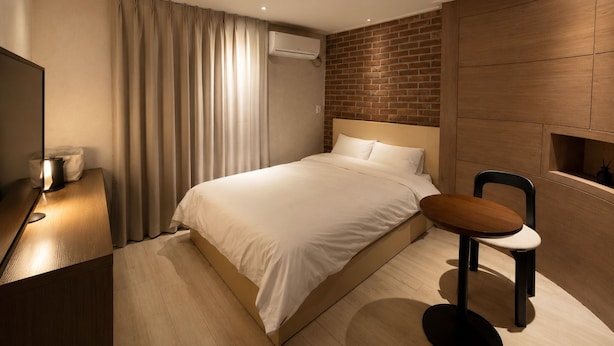 A modern hotel room with a bed, a desk, a chair, and a TV. - Stay PAUSE (BUCHEON)