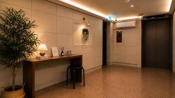 Eine Hotelhalle mit einer Rezeption, einem Blumentopf, einer Wandpflanze und einem Aufzug.