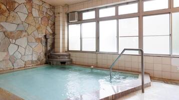 Ein Innenpool mit Steinwänden und großen Fenstern.