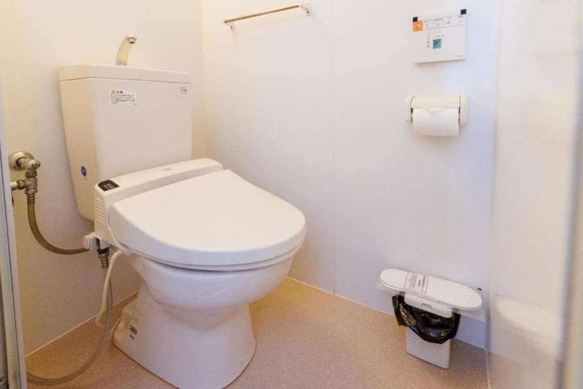 A standard bathroom with a toilet, a hand dryer, and a paper towel dispenser.