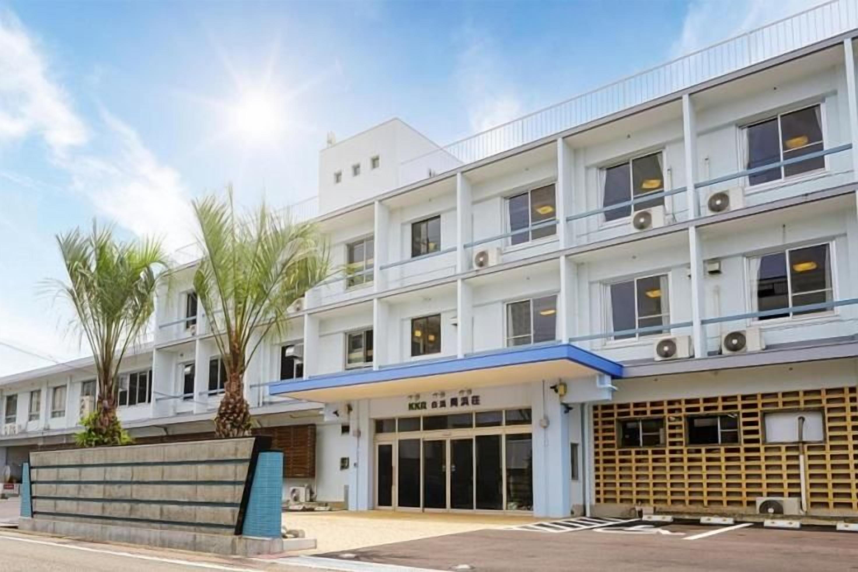 Un hôtel à plusieurs étages, doté d’un auvent bleu, d’une entrée couverte et d’un espace de stationnement.
