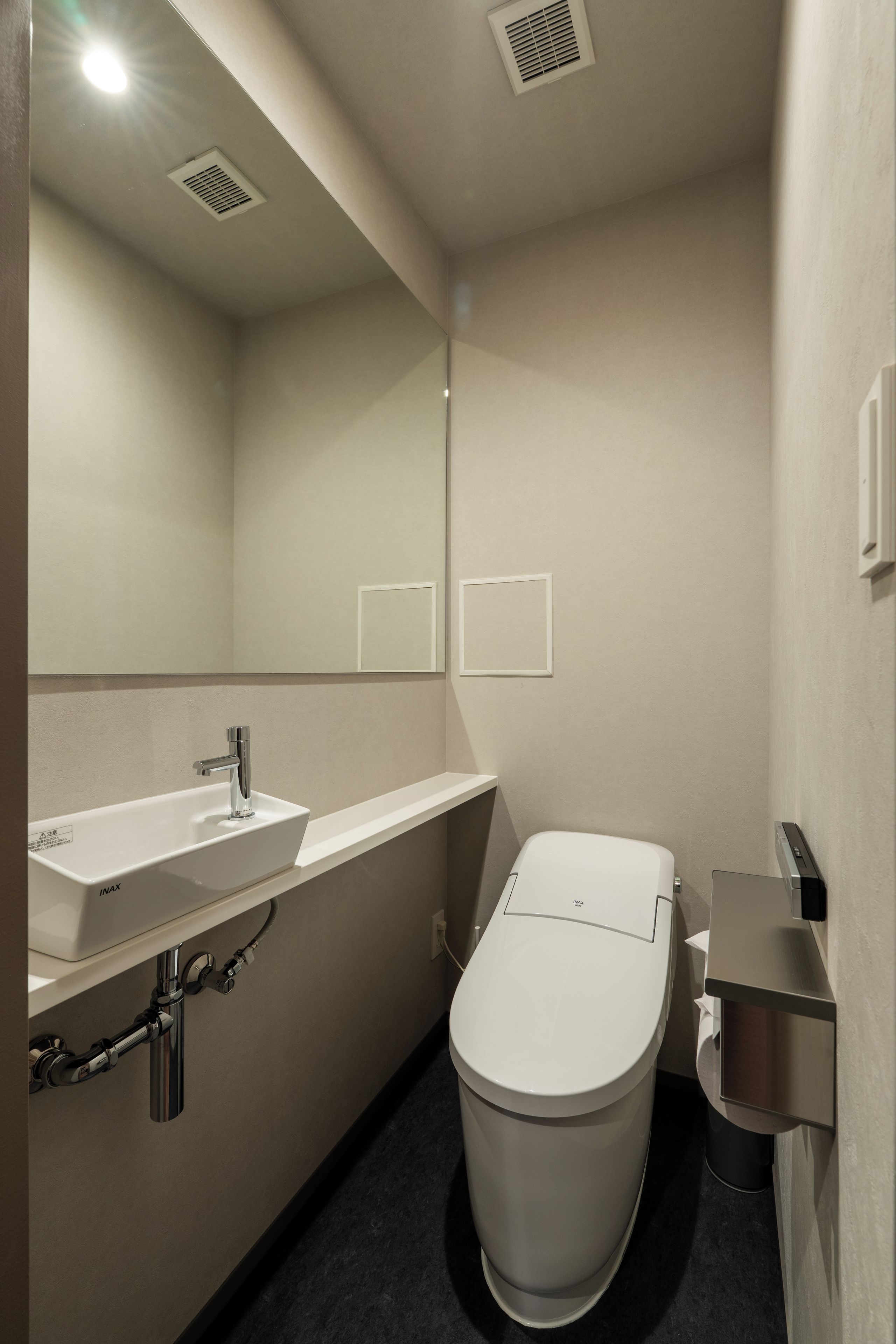 A modern bathroom with a white sink, a toilet, and a mirror.