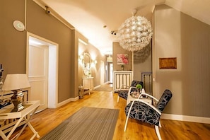 A hallway with a chandelier, a sofa, and a dining table. - Hotel Zum Dorfbrunnen (Schleusingen)
