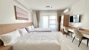 Una camera d'albergo con due letti, una scrivania, una televisione e una finestra con tende.