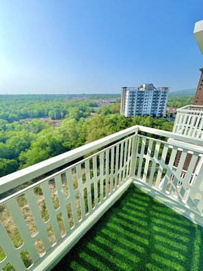 A balcony with a white railing overlooking a green landscape and buildings. - Royal Oceancrest Panglao 1 (Dauis)
