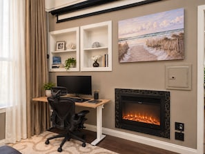 A home office with a desk, computer, and fireplace.