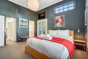 A bedroom with a large bed, a bedside table, a chair, a wardrobe, and a window. - Desert Muse by Homello (Auckland)