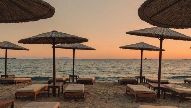 Een strand met ligbedden en parasols van riet.