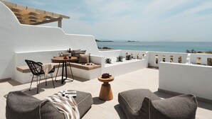 Een terras met een tafel, stoelen en uitzicht op zee.