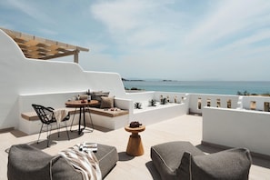 A terrace with a table, chairs, and a view of the sea. - Nikos & Maria Studios (Naxos)