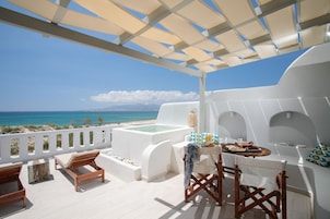 Una terraza con vistas al mar, un jacuzzi y una mesa de comedor con sillas.