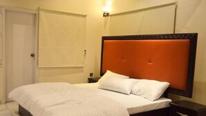 Una habitación de hotel con una cama, una mesita de noche y una puerta.