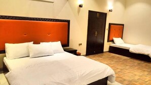 Una habitación de hotel con una cama grande, una cama más pequeña, un armario y una puerta con una cruz.
