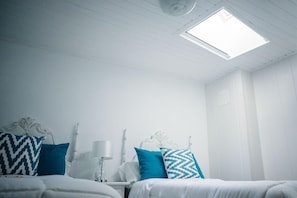 A room with two beds, a nightstand, a lamp, and a ceiling light fixture. - Casa a Boleriã±a 1 (Poio)