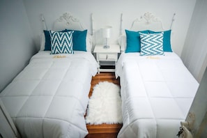 A double bed room with white bedding and teal pillows, a small bedside table with a lamp, and a fluffy rug on the floor. - Casa a Boleriã±a 1 (Poio)