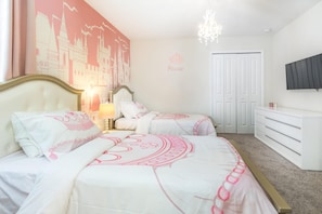 Quarto com duas camas, um lustre, um guarda-roupa e uma parede com padrão de castelo.
