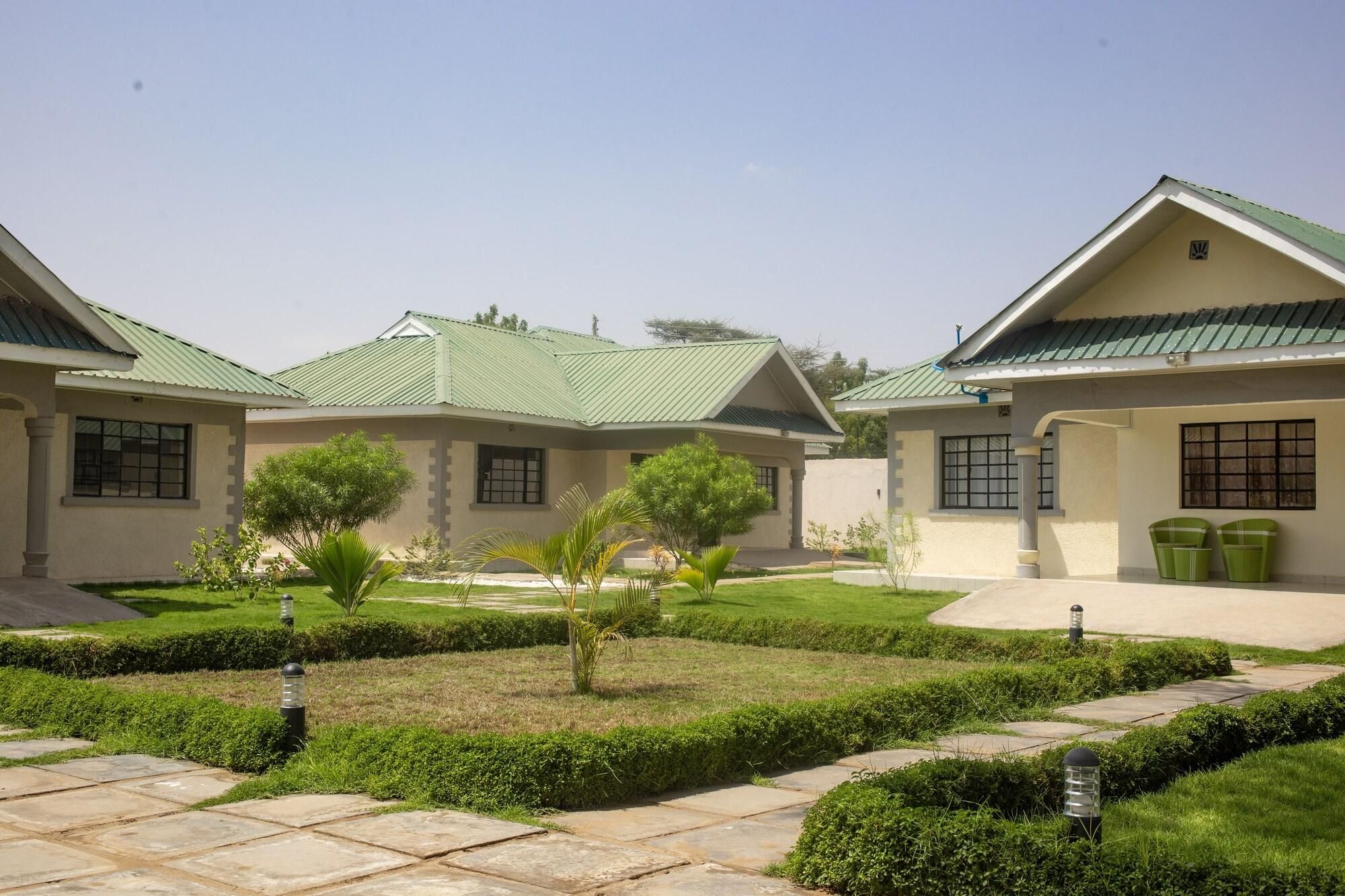 A residential building with a symmetrical design, featuring a central courtyard with a paved walkway, surrounded by manicured lawns and small trees.