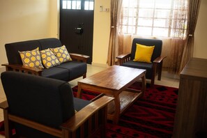 A living room with a sofa, two armchairs, a coffee table, and a patterned rug. - Lodwar Acacia Residences (Lodwar)