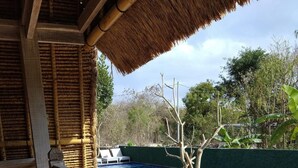 A wooden deck with a pool, a thatched roof, and a view of the surrounding greenery. - Honeybee Huts (Lembongan Island)