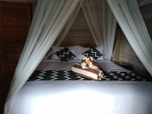 Uma cama com dossel, almofadas e um objeto decorativo sobre ela.