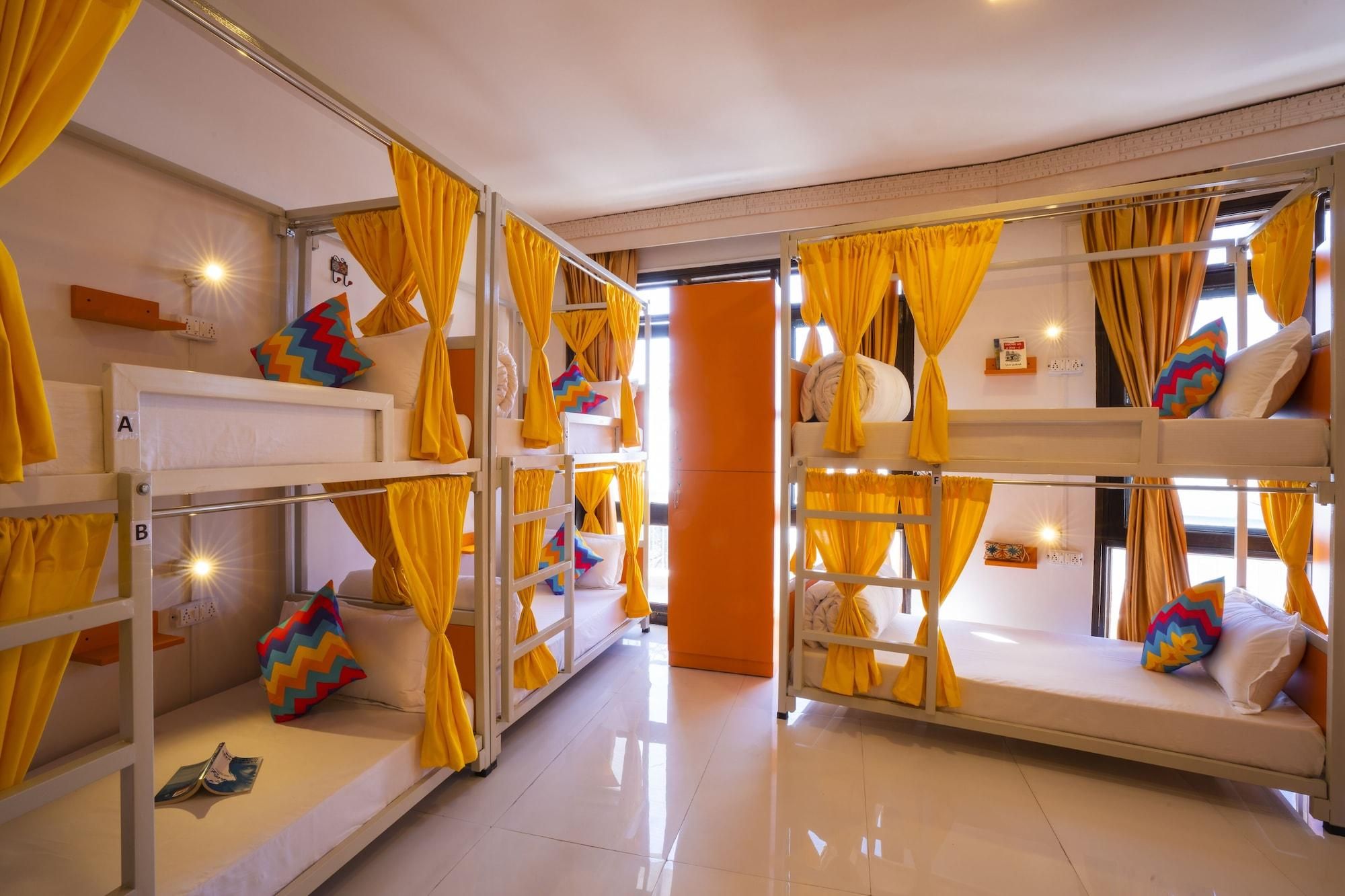 A room with bunk beds, each with yellow curtains, and a bright, tiled floor.