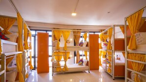 Um dormitório em beliche com cortinas amarelas e chão ladrilhado.
