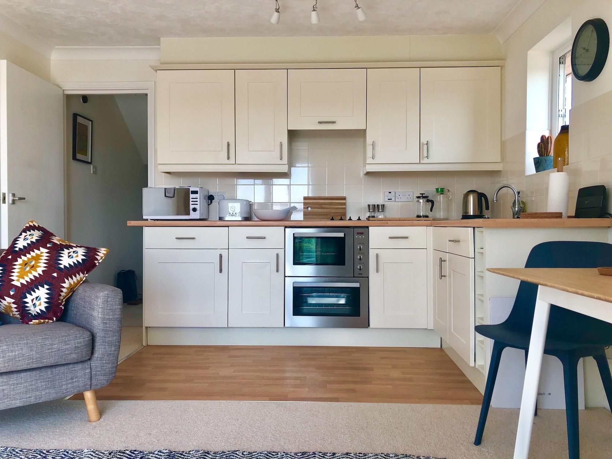 A compact kitchen with white cabinets, a microwave, a toaster, and an oven.