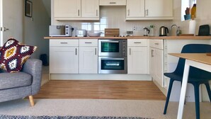 A compact kitchen with white cabinets, a microwave, a toaster, and an oven. - Waterside (Rye)