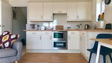 A compact kitchen with white cabinets, a microwave, a toaster, and an oven.