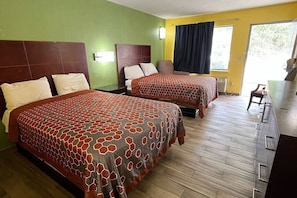 Una habitación de hotel con dos camas, un escritorio y vistas al exterior.
