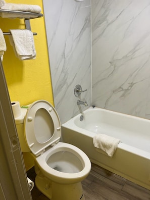 Un baño con inodoro, bañera y pared de mármol.