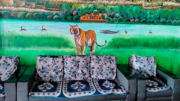 Une fresque représentant un tigre sur un canapé agrémenté de coussins à motifs floraux.