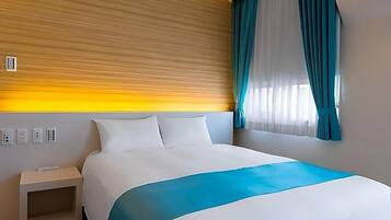 A hotel room with a bed, a nightstand, a window with curtains, and a wall with a textured pattern.
