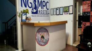 A reception desk with a sign for NGBMPC Hostel, a logo for Galerian Business Men, and several framed documents on the wall. - Ngbmpc Hostel (Puerto Galera)
