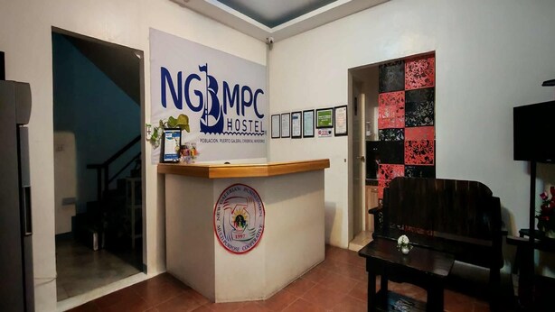 A reception area with a counter, framed certificates, and a logo. - Ngbmpc Hostel (Puerto Galera)