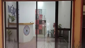 A reception area with a counter, a logo, and a wall with a circular emblem. - Ngbmpc Hostel (Puerto Galera)