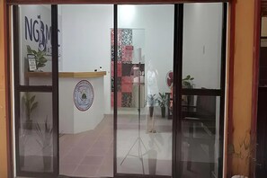 A reception area with a counter, a logo, and a wall with a circular emblem. - Ngbmpc Hostel (Puerto Galera)