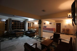 A cozy living room with a sofa, a coffee table, and a dining area with chairs and a table. - Spiti Heritage Himalayan Brothers (Spiti)