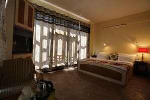 A hotel room with a bed, a desk, a chair, a television, and a window with curtains. - Spiti Heritage Himalayan Brothers (Spiti)
