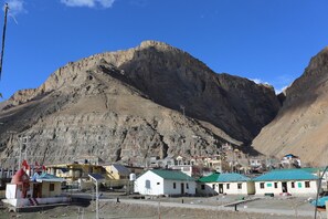A mountainous landscape with a small settlement featuring simple buildings with green roofs. - Spiti Heritage Himalayan Brothers (Spiti)