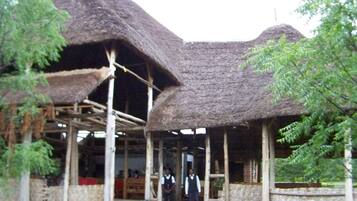 A traditional thatched-roof structure with a covered entrance and a wooden staircase leading inside.