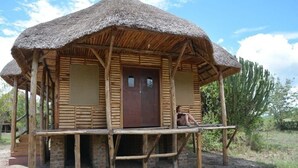 Una estructura rústica de madera con techo de paja y un porche de madera.