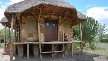 A rustic wooden structure with a thatched roof and a wooden porch.