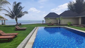 A swimming pool with a view of the ocean, surrounded by palm trees and lounge chairs. - The Kelong Trikora Resort - Bintan Island (Bintan Island)