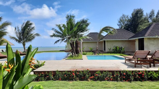 A resort with a swimming pool, lounge chairs, and a view of the ocean. - The Kelong Trikora Resort - Bintan Island (Bintan Island)